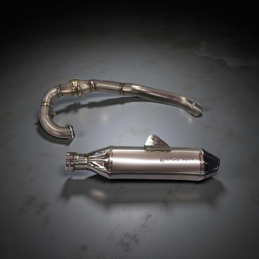 Polished VANDEMON motorcycle exhaust system with curved pipe and conical muffler, featuring precision welds and clamps.