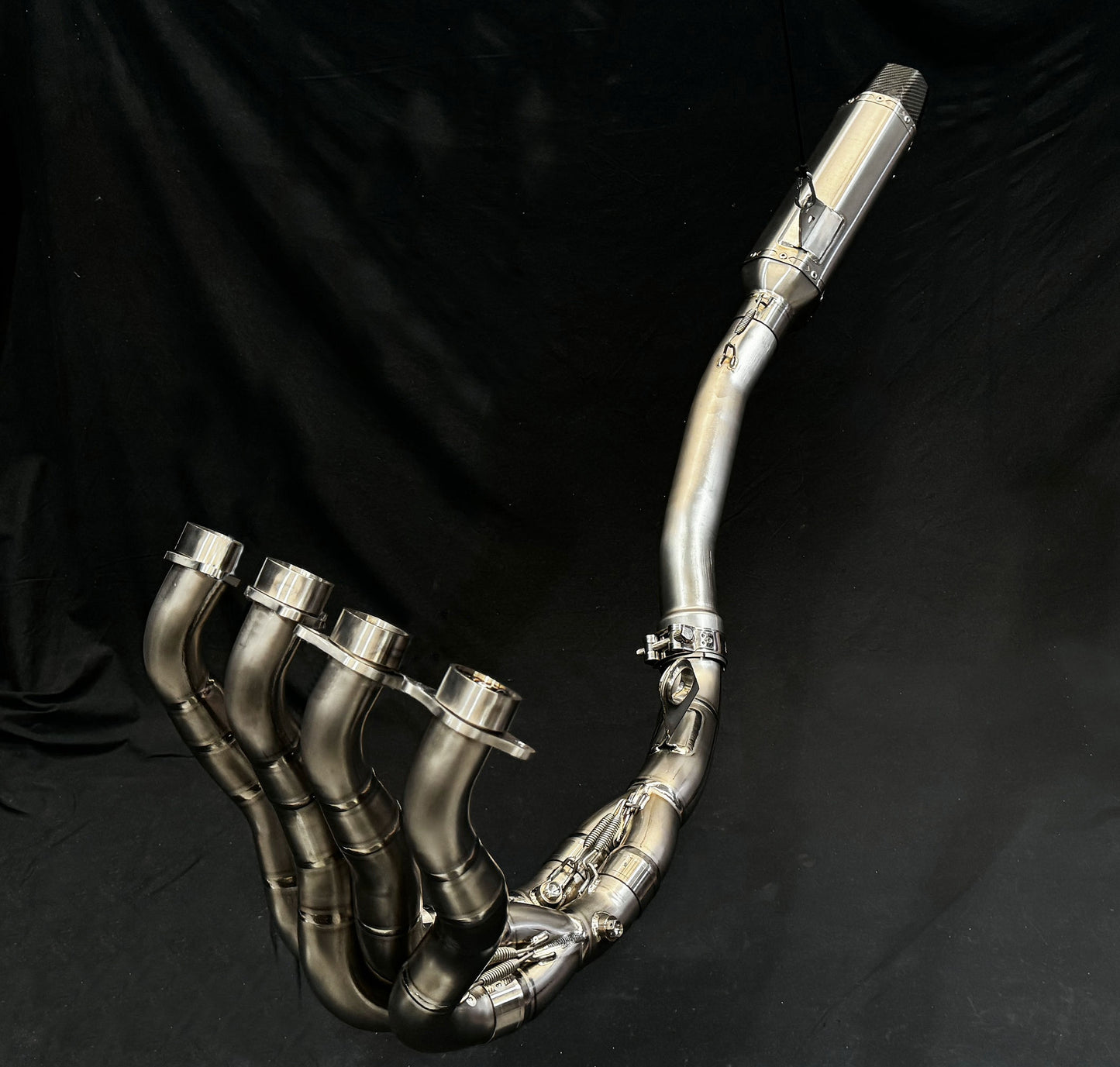 Close-up of a motorcycle exhaust pipe against a solid black background