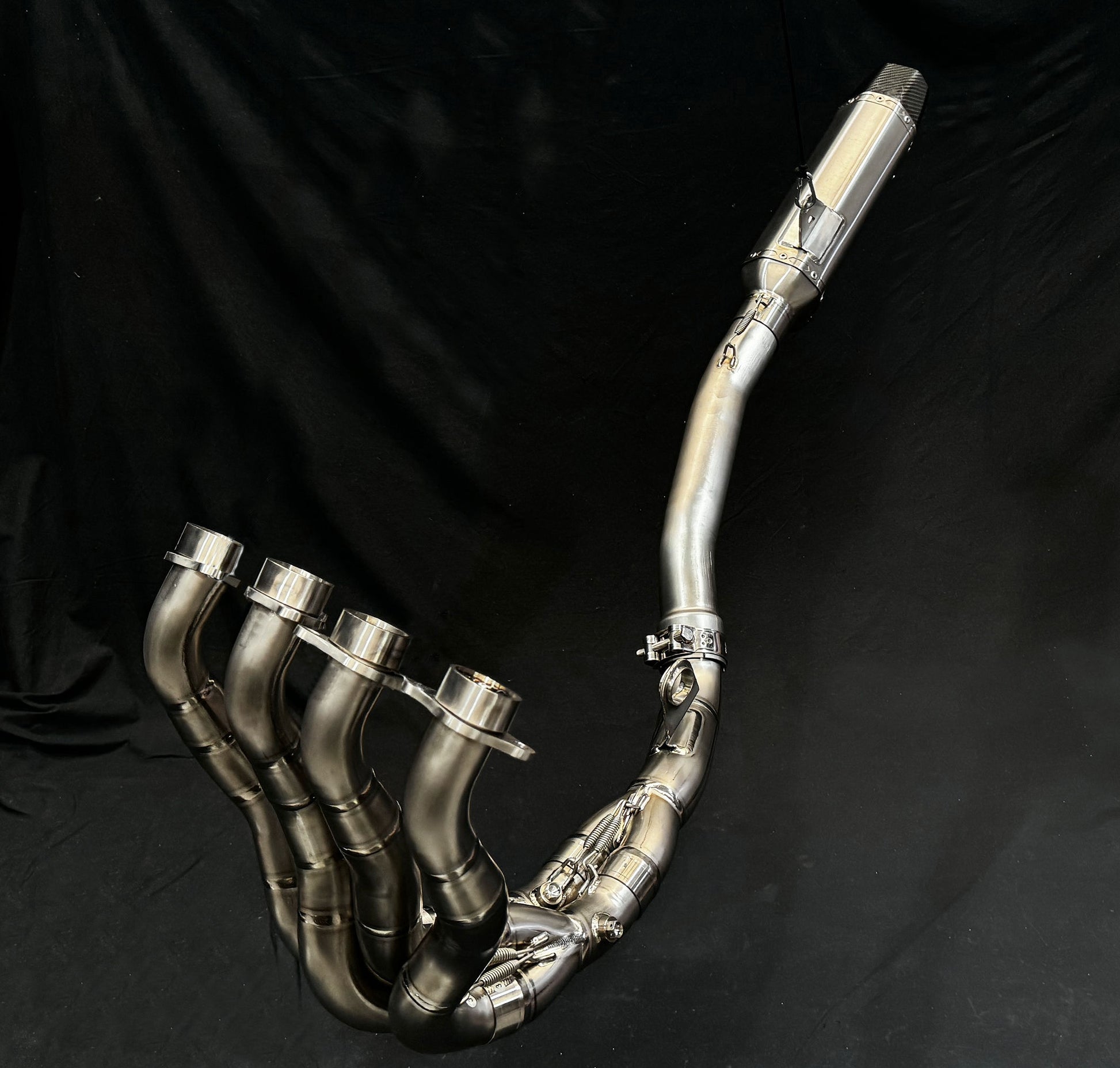 Close-up of a motorcycle exhaust pipe against a solid black background