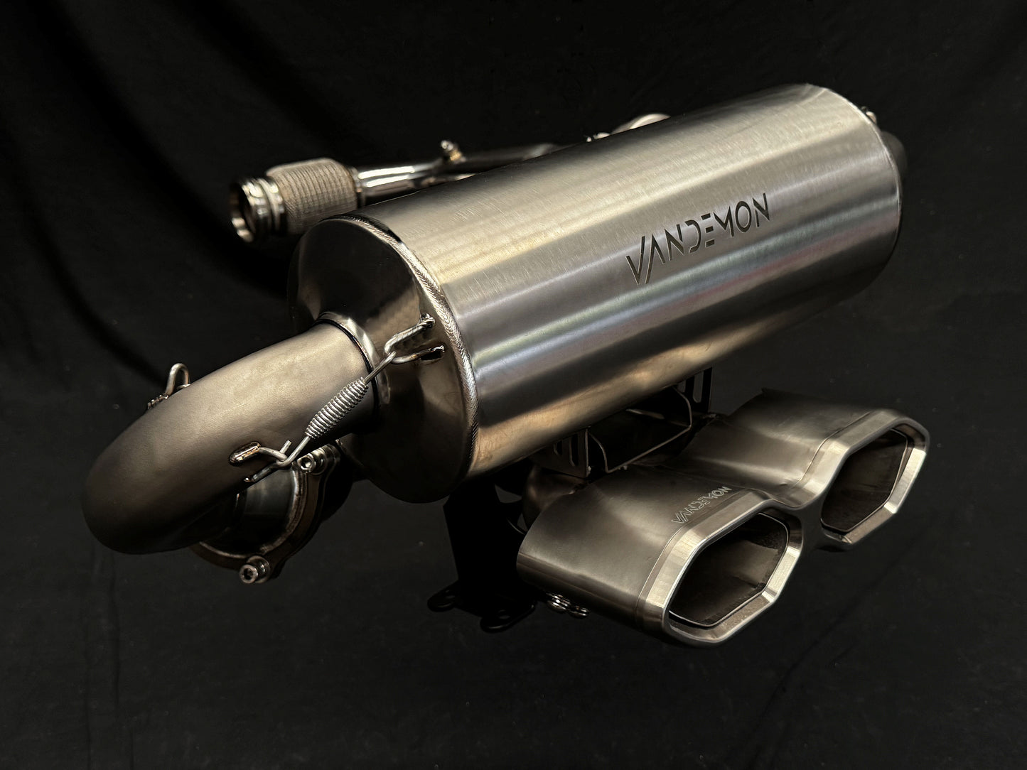 Metallic, sleek motorcycle exhaust close-up against dark background.