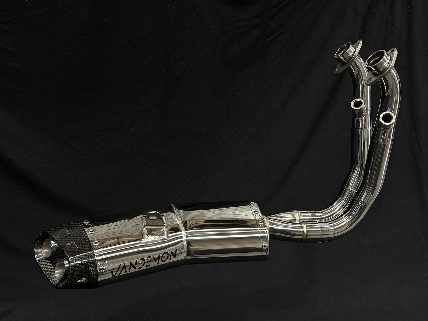 Detailed view of a motorcycle exhaust pipe set against a black backdrop