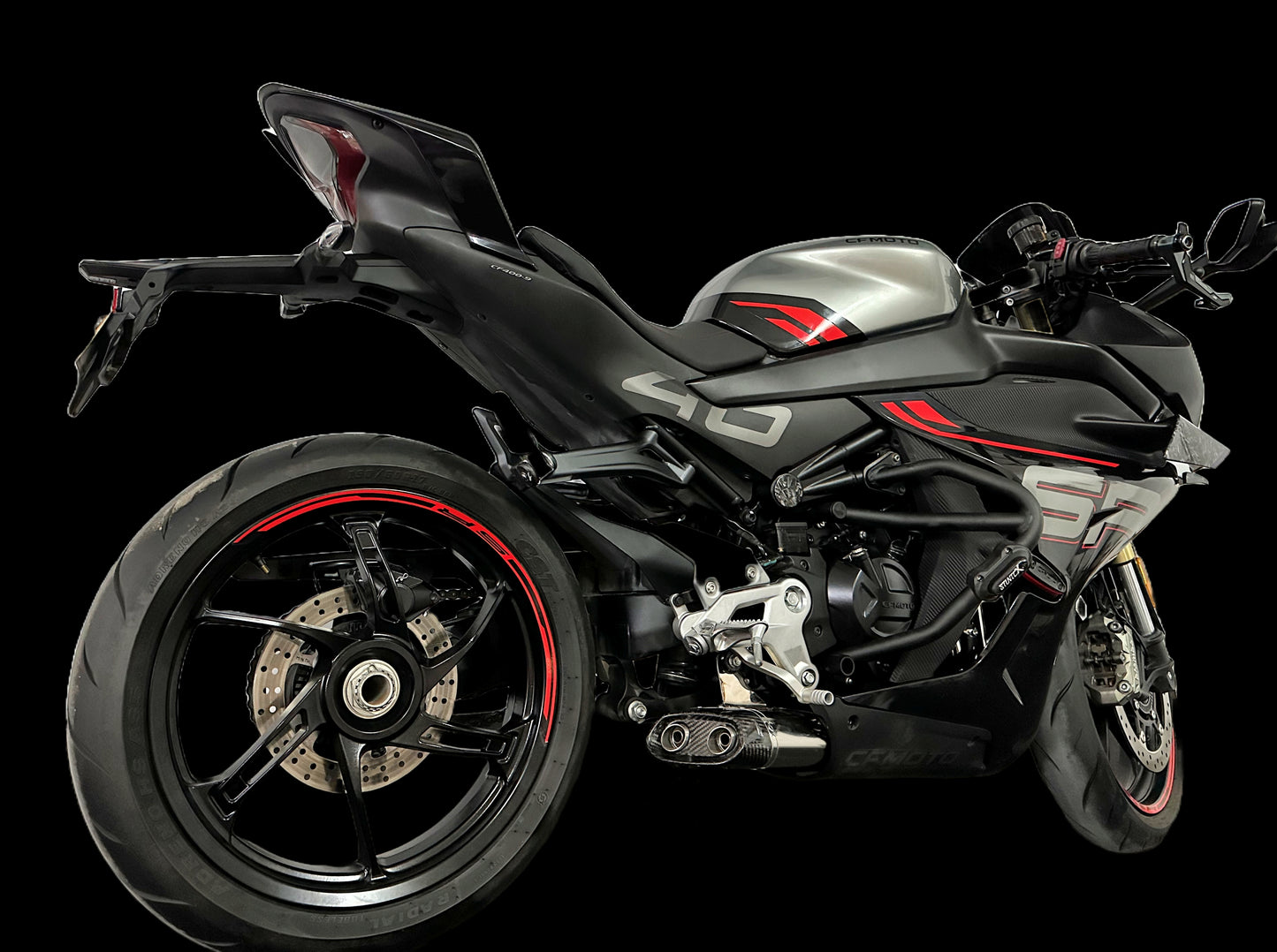 A striking black and red motorcycle displayed on a black background, emphasizing its modern features and bold color scheme.
