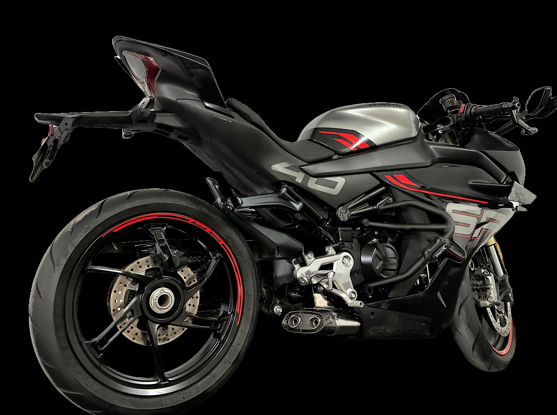 A striking black and red motorcycle displayed on a black background, emphasizing its modern features and bold color scheme.
