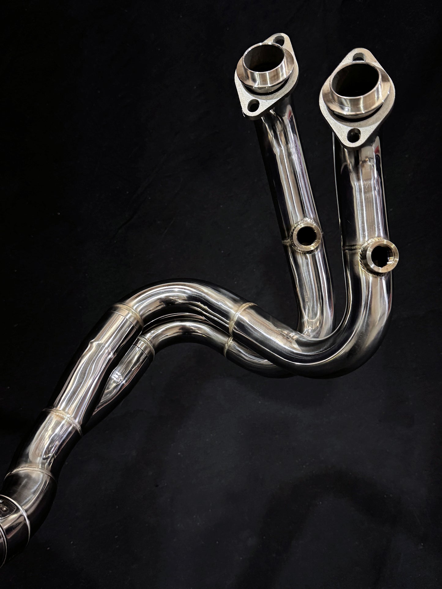 Detailed view of sleek motorcycle exhaust system on dark background.