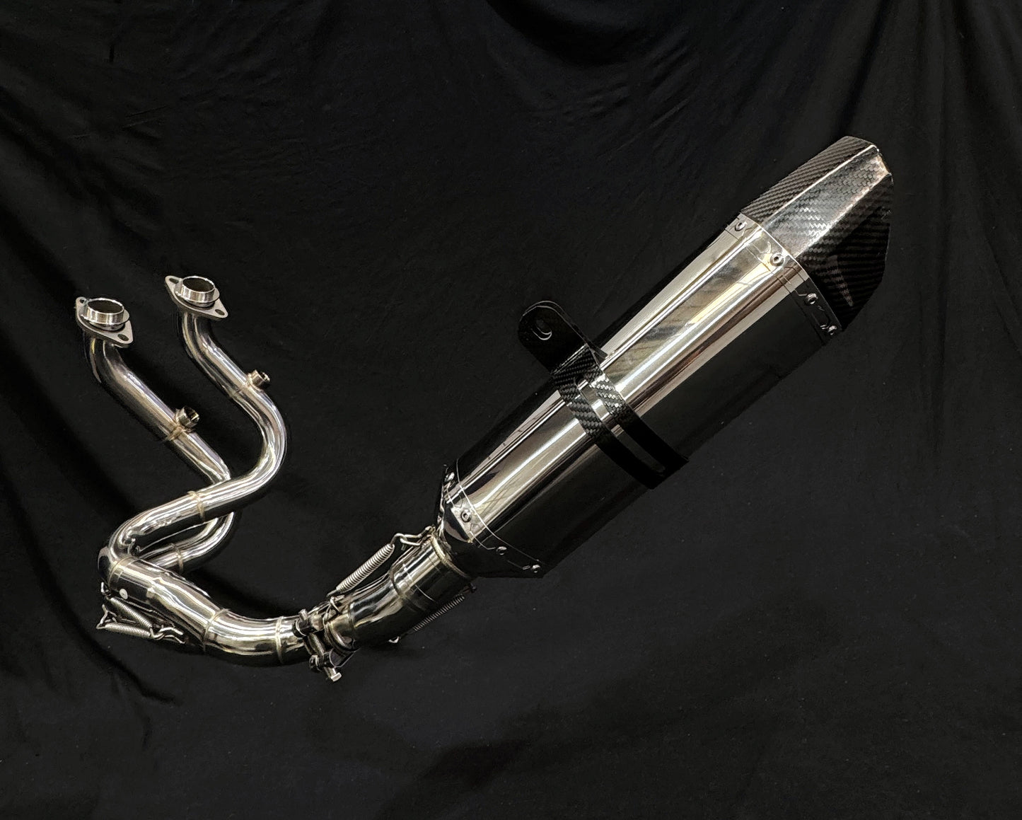 Light reflecting off metallic dual-exhaust motorcycle system close-up.