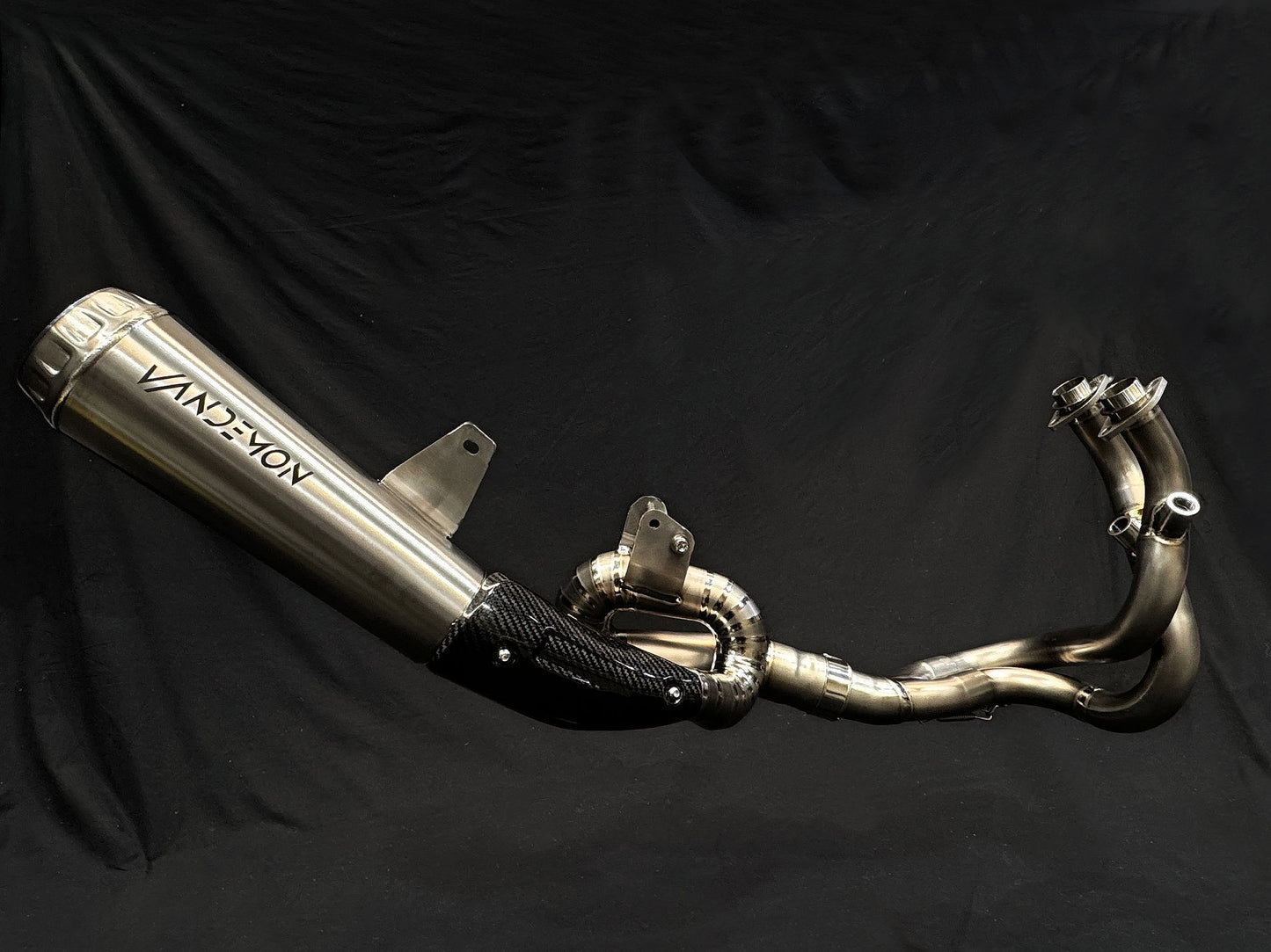Close-up of motorcycle dual-exhaust system, shiny metallic finish.