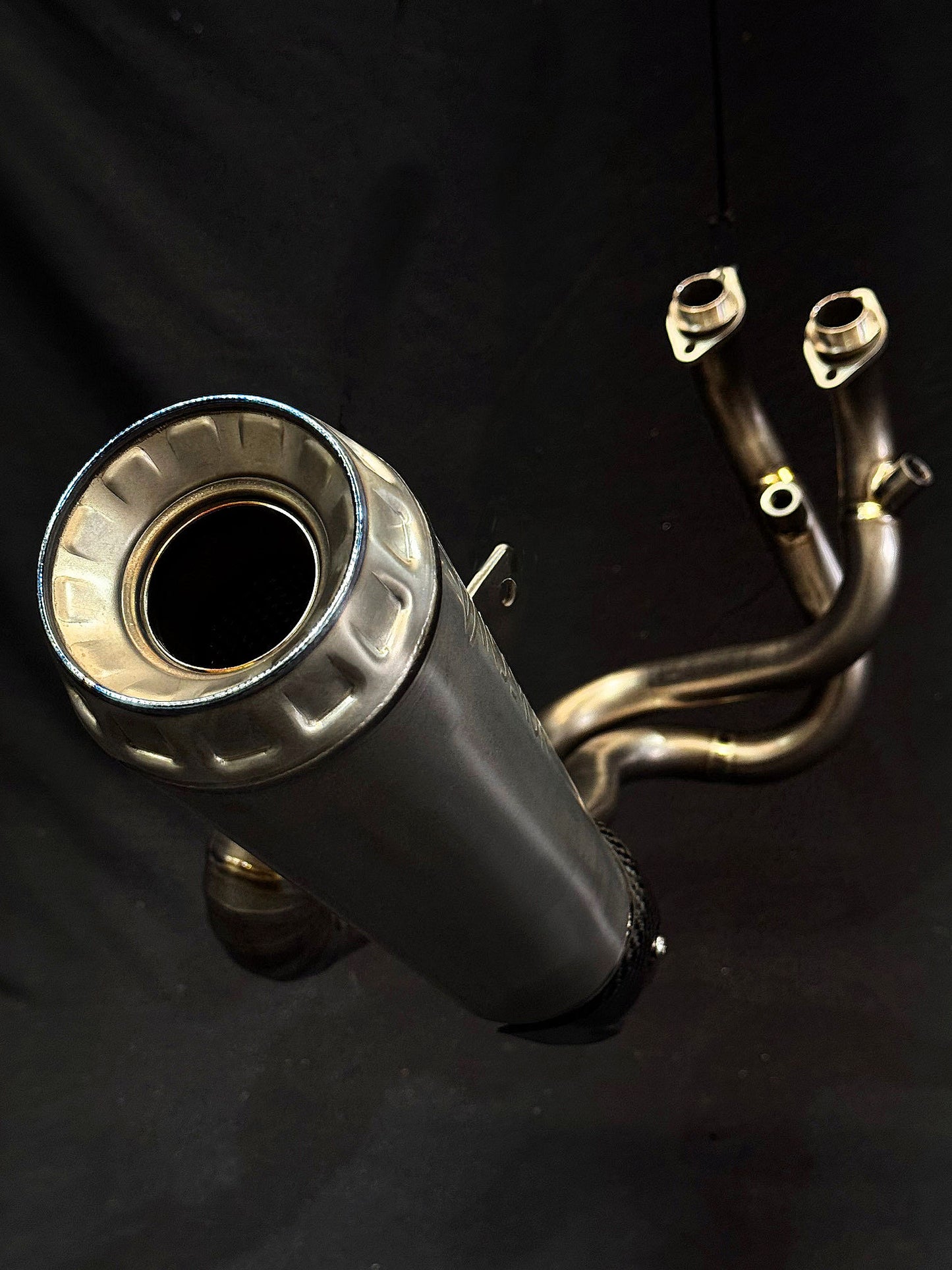 Intricate detailing on dual-exhaust motorcycle system in dark setting.