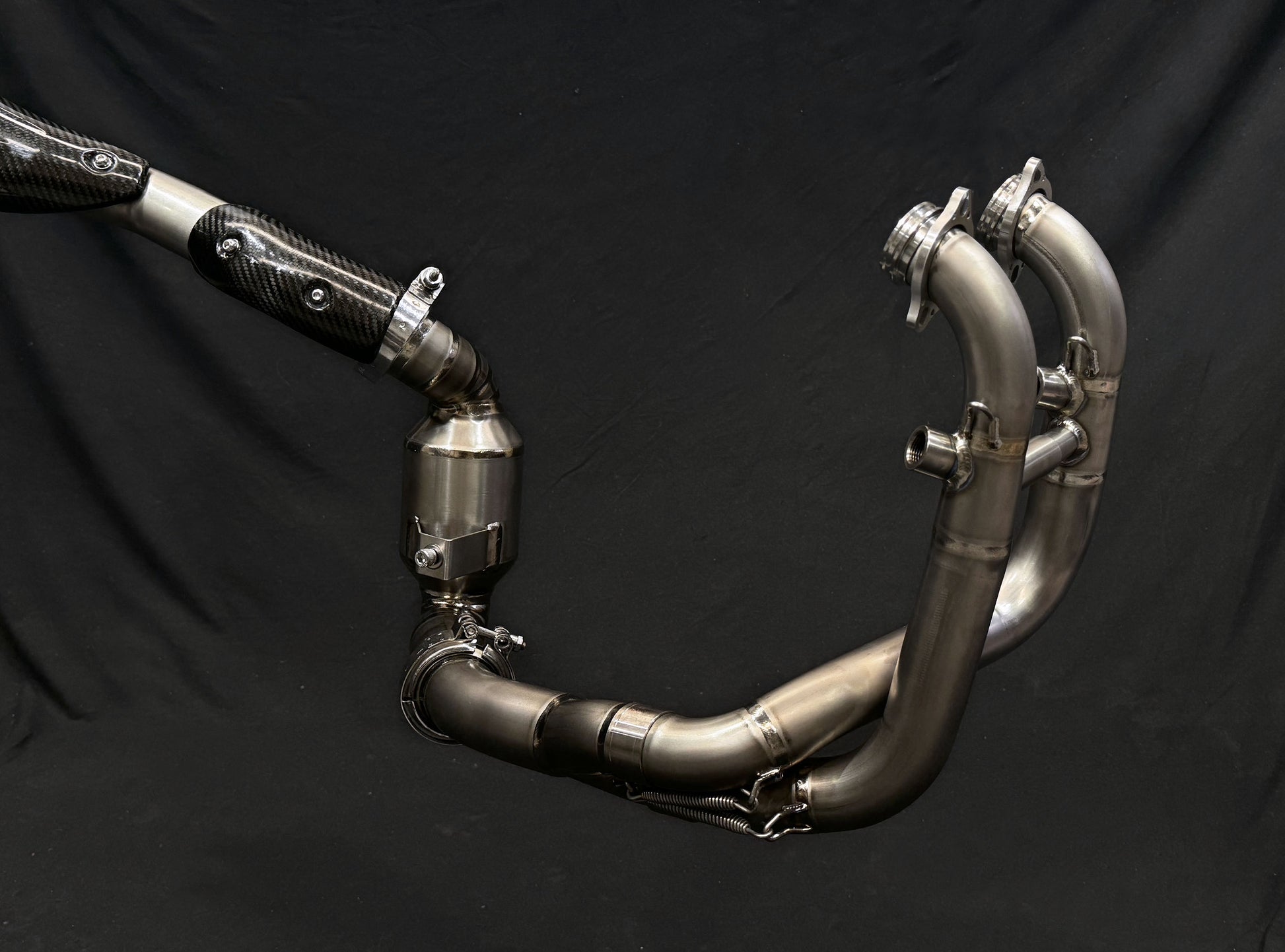 A sleek motorcycle exhaust pipe displayed on a black background