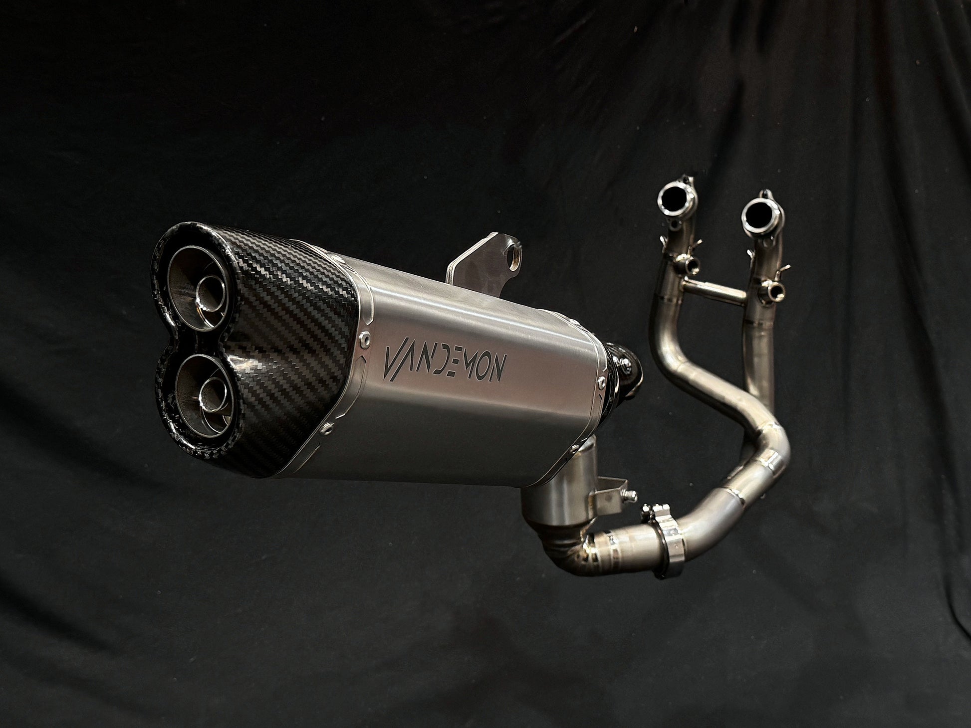 Detailed view of a motorcycle exhaust pipe set against a black backdrop