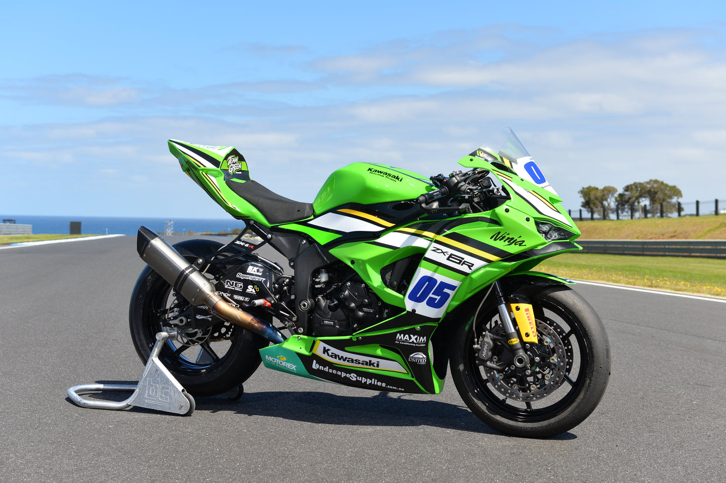 A green motorcycle displayed in the middle of the road.