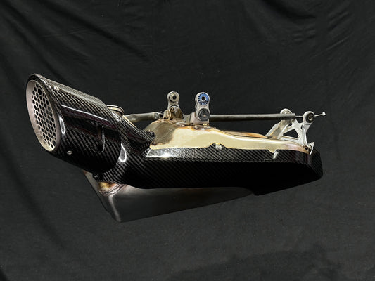 A motorcycle's Muffler Carbon Fibre Bling with a Black backdrop.