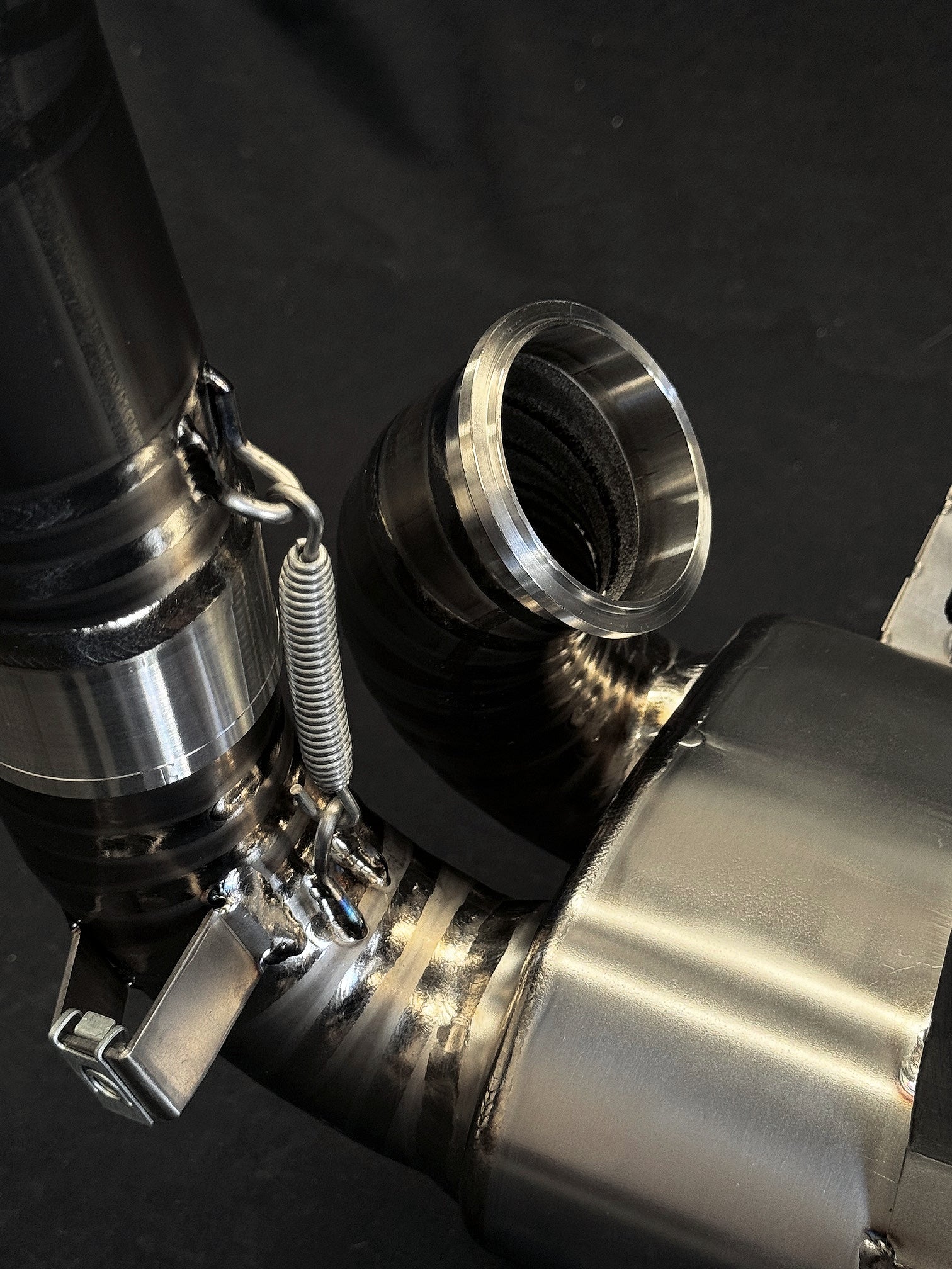 Sleek motorcycle exhaust system reflecting light on dark background.
