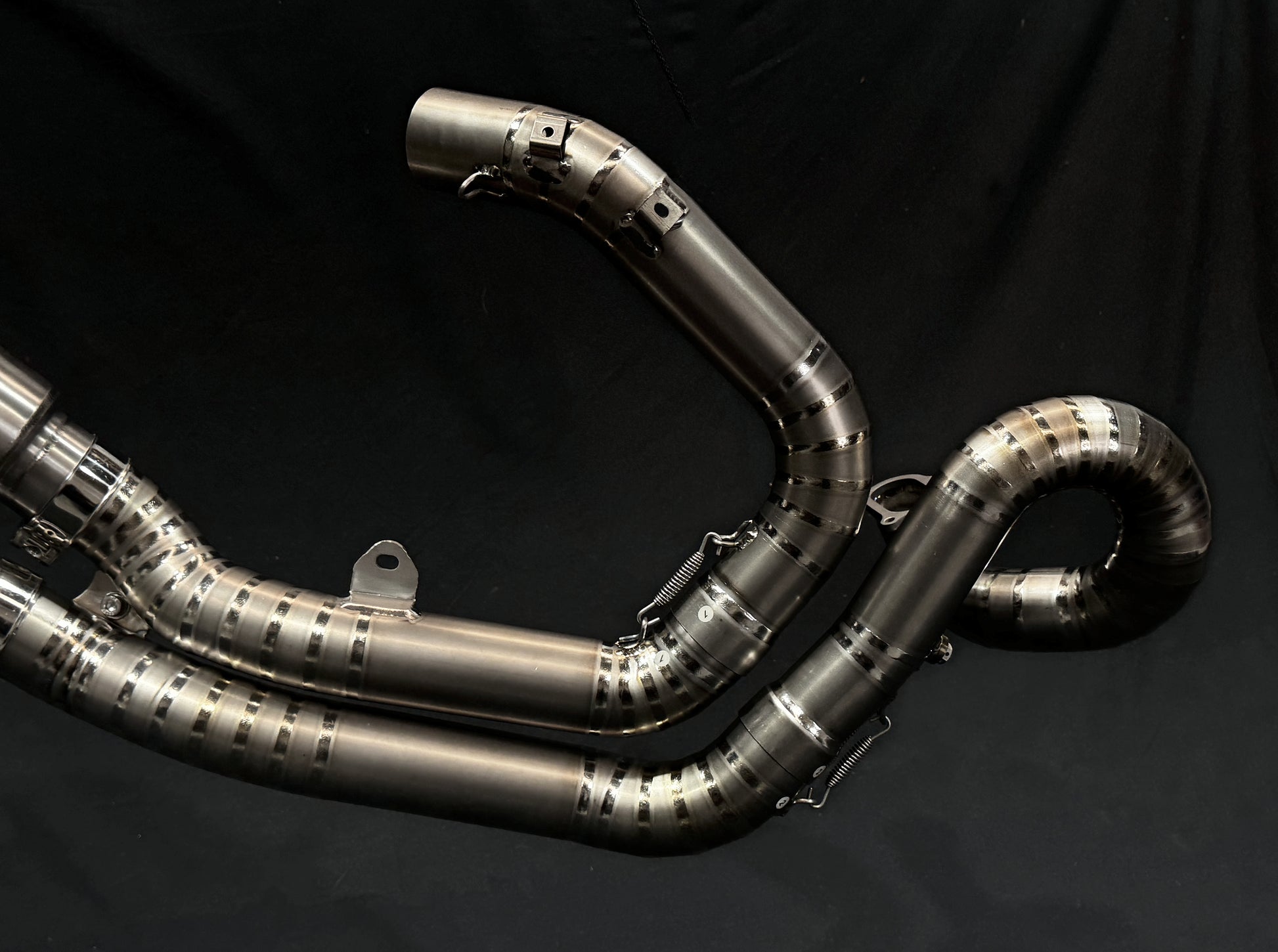 Titanium exhausts headers with a black backdrop.