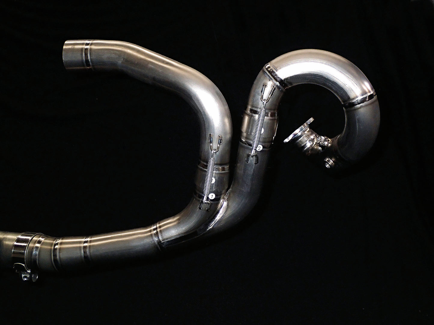 Dark background highlighting motorcycle dual-exhaust system.
