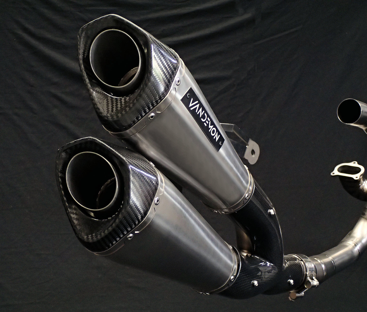 Light reflecting off metallic twin mufflers motorcycle system close-up.