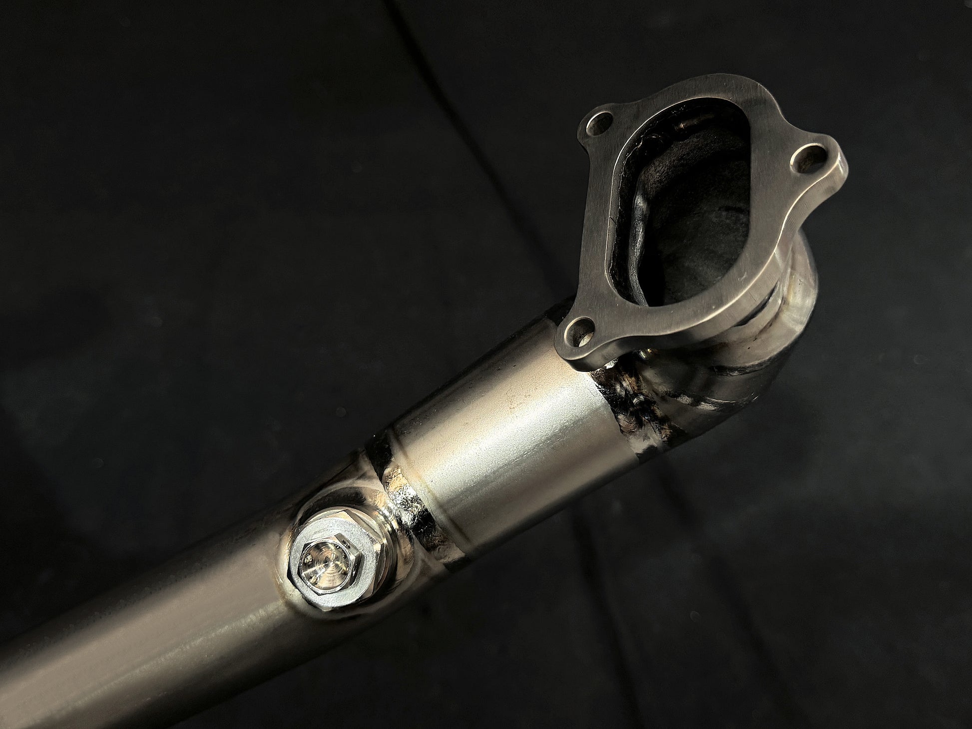 Metallic motorcycle exhaust reflecting light, close-up.