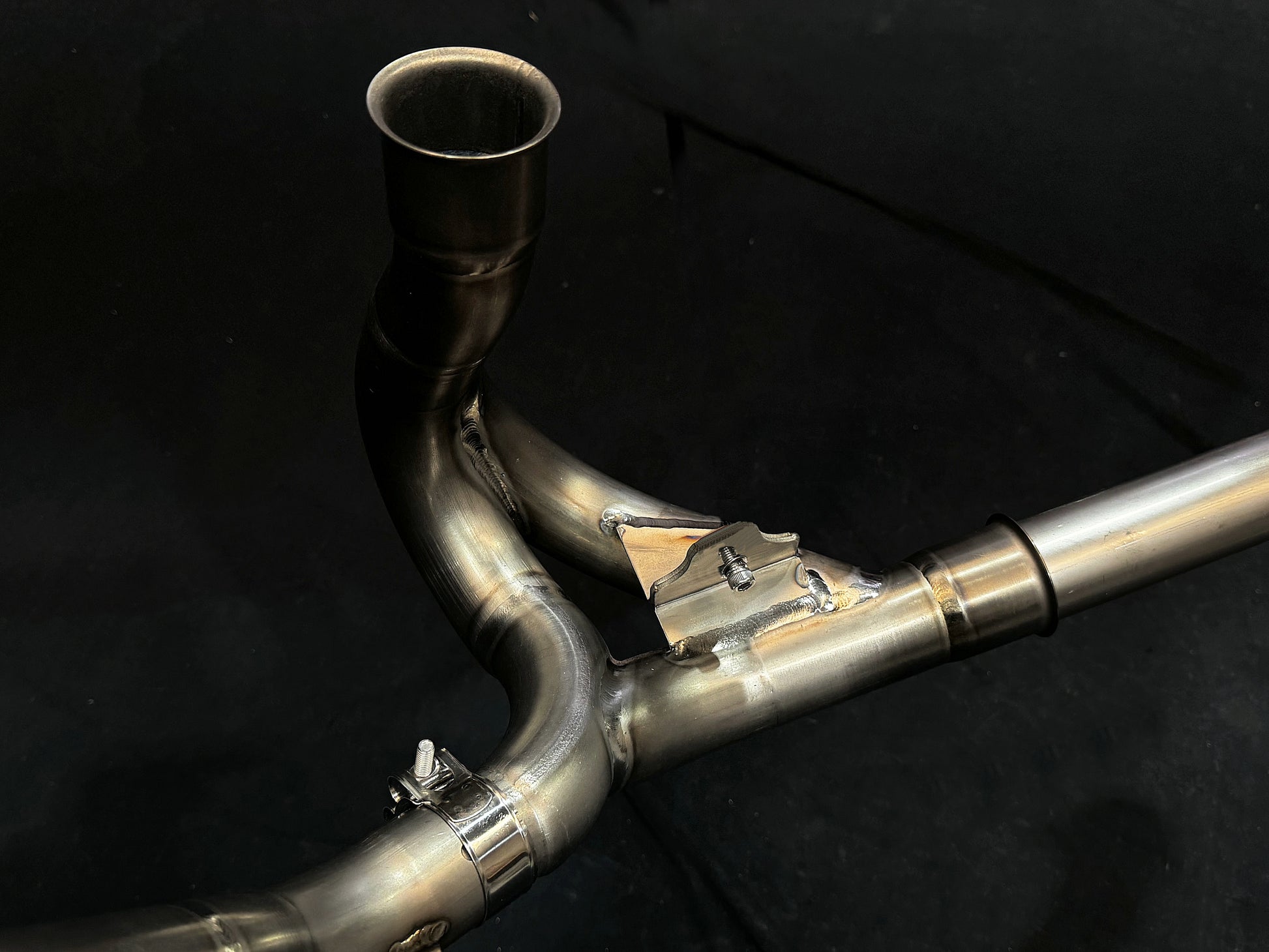 Close-up of motorcycle dual-exhaust system, shiny metallic finish.
