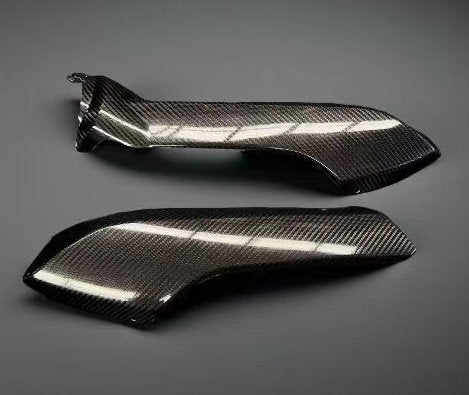 Two carbon fibre motorcycle fairing panels on a gray background