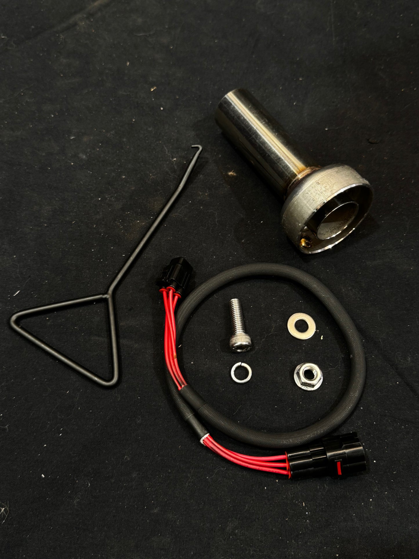 Automotive parts in metal and carbon fiber on dark surface.