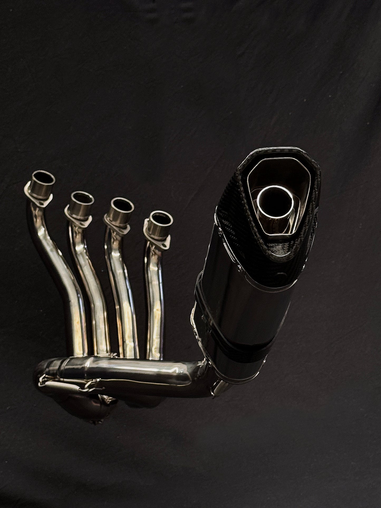 A detailed black and white image of a motorcycle exhaust pipe