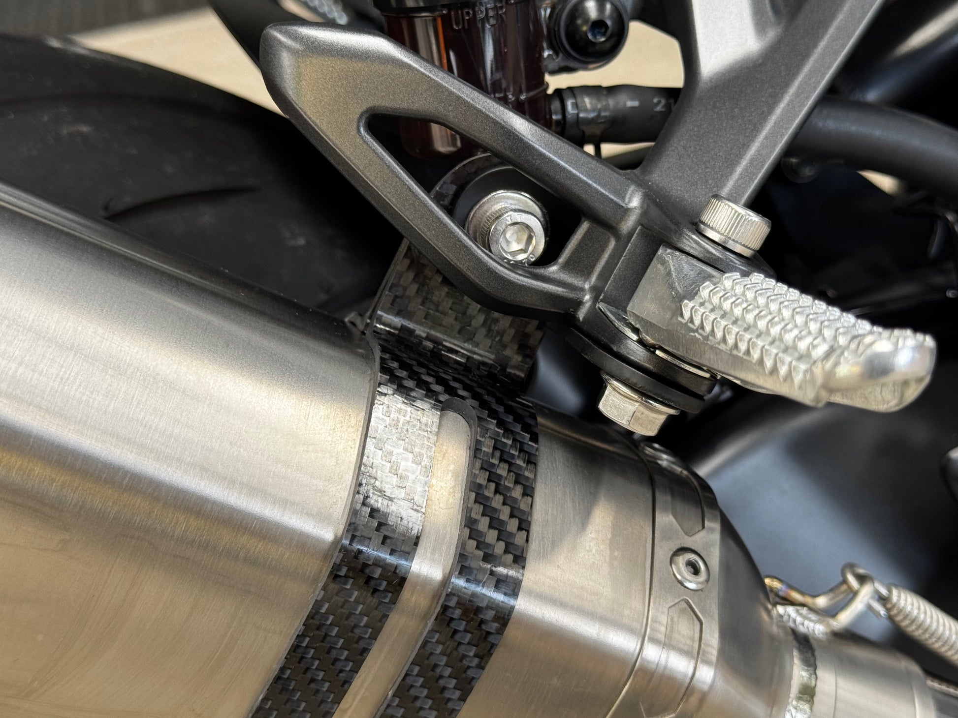 Close-up of a motorcycle's exhaust pipe and its peg.