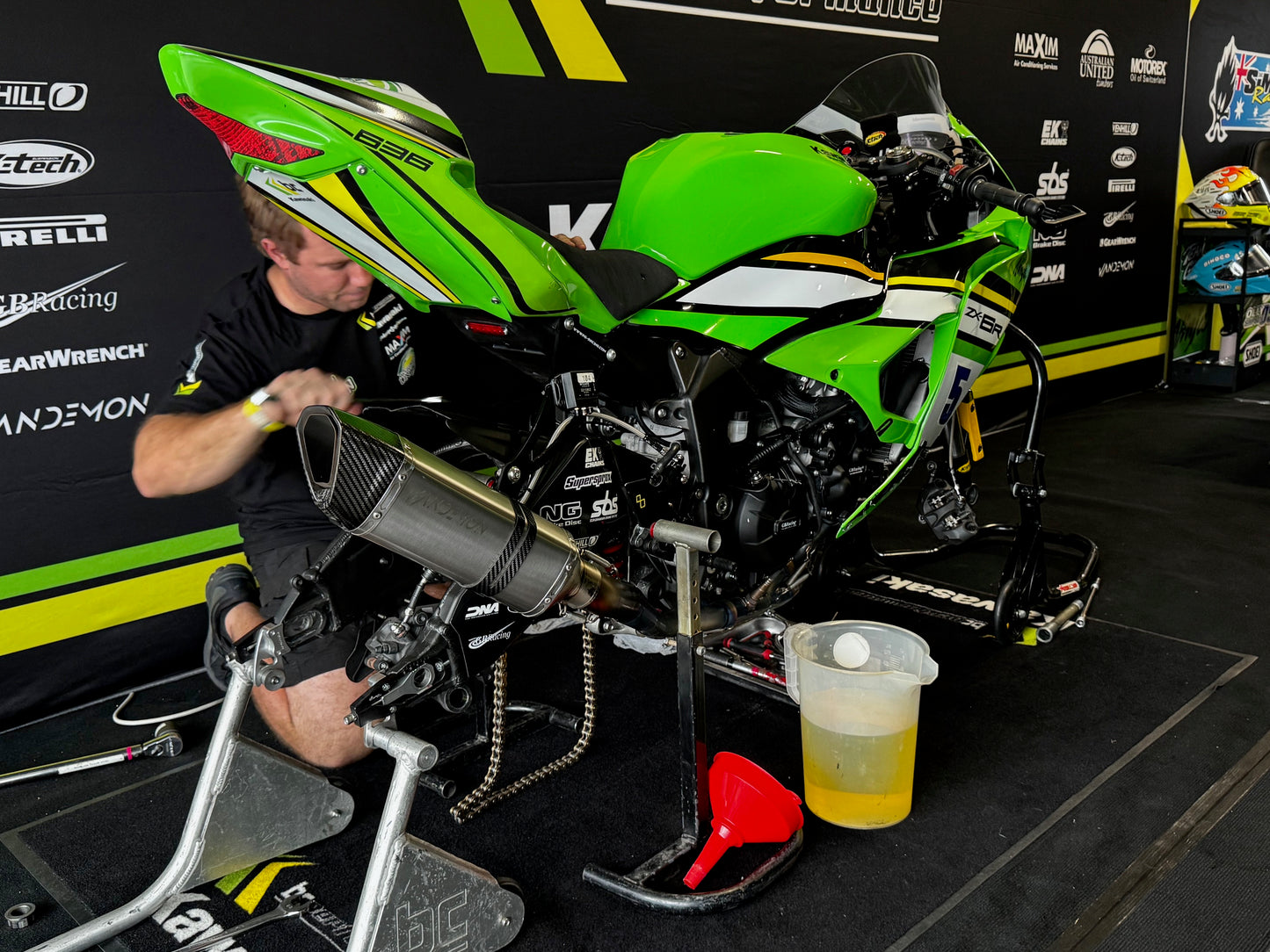 A man fixing a green motorcycle.