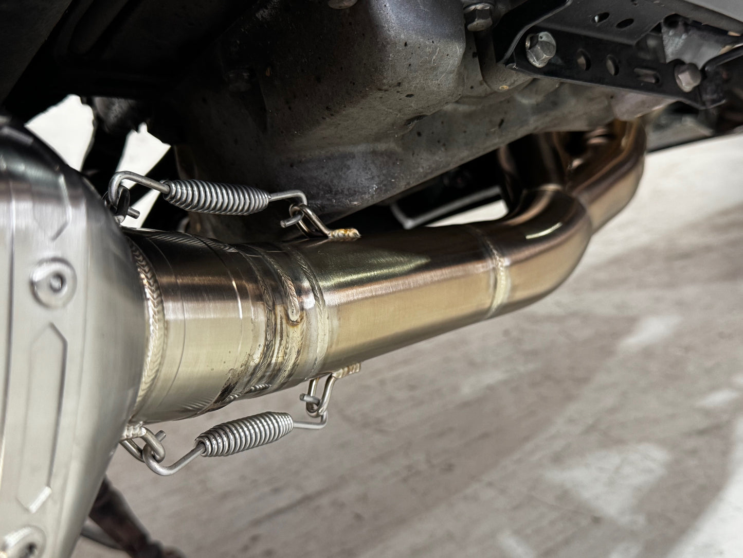 A Close up view of a motorcycle's muffler elbow.