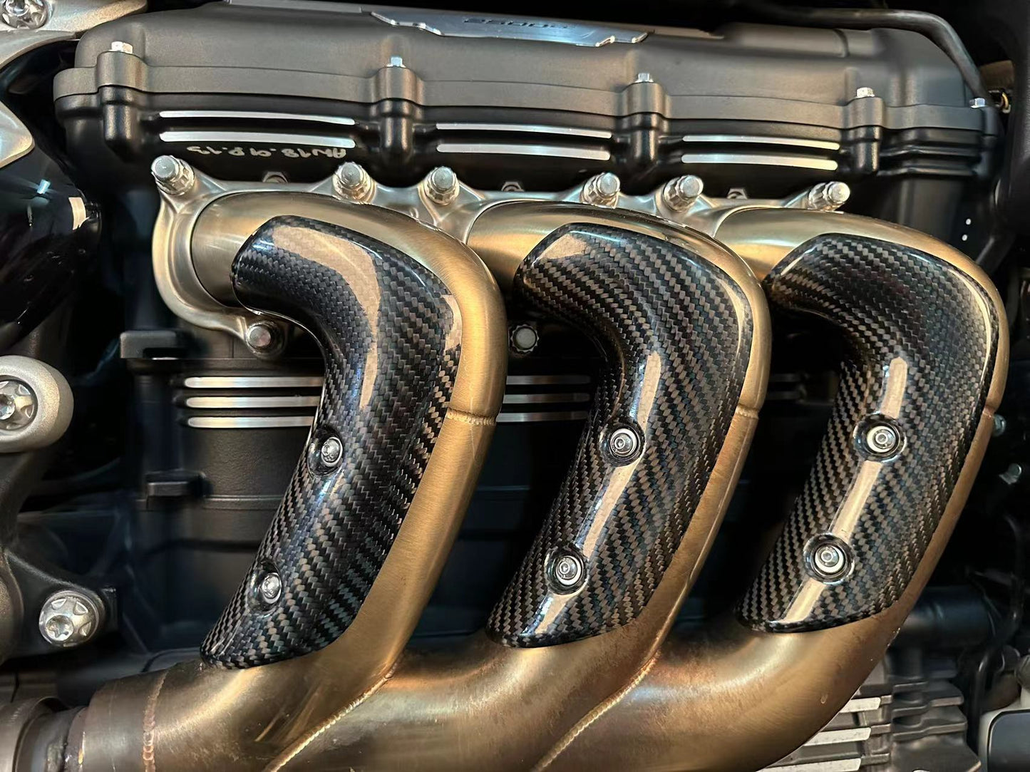 Close-up of motorcycle exhaust pipes featuring a sleek carbon fiber cover