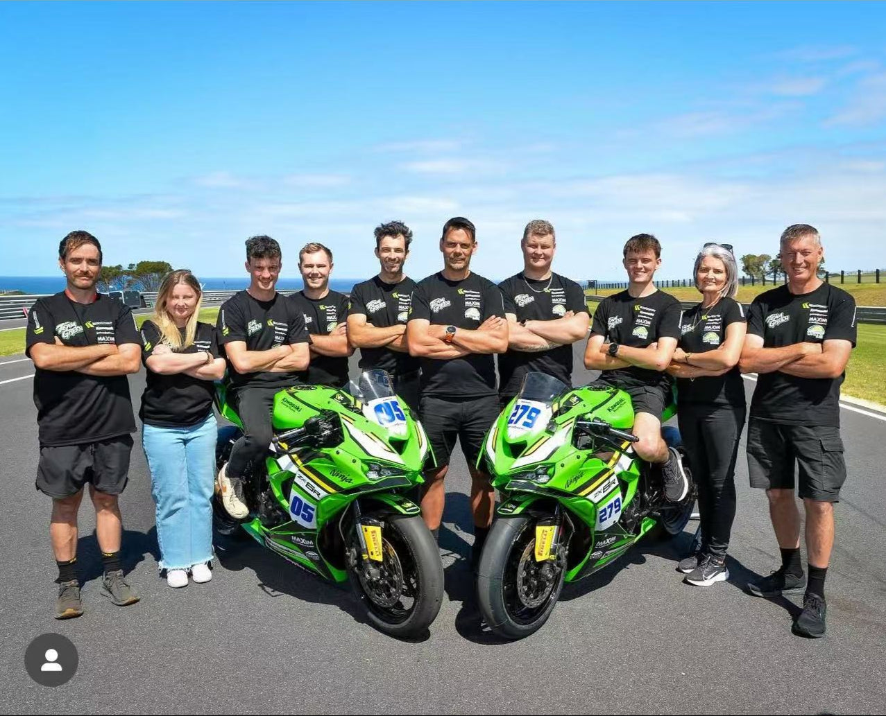 Team of riders and mechanics pose together for a group photo,