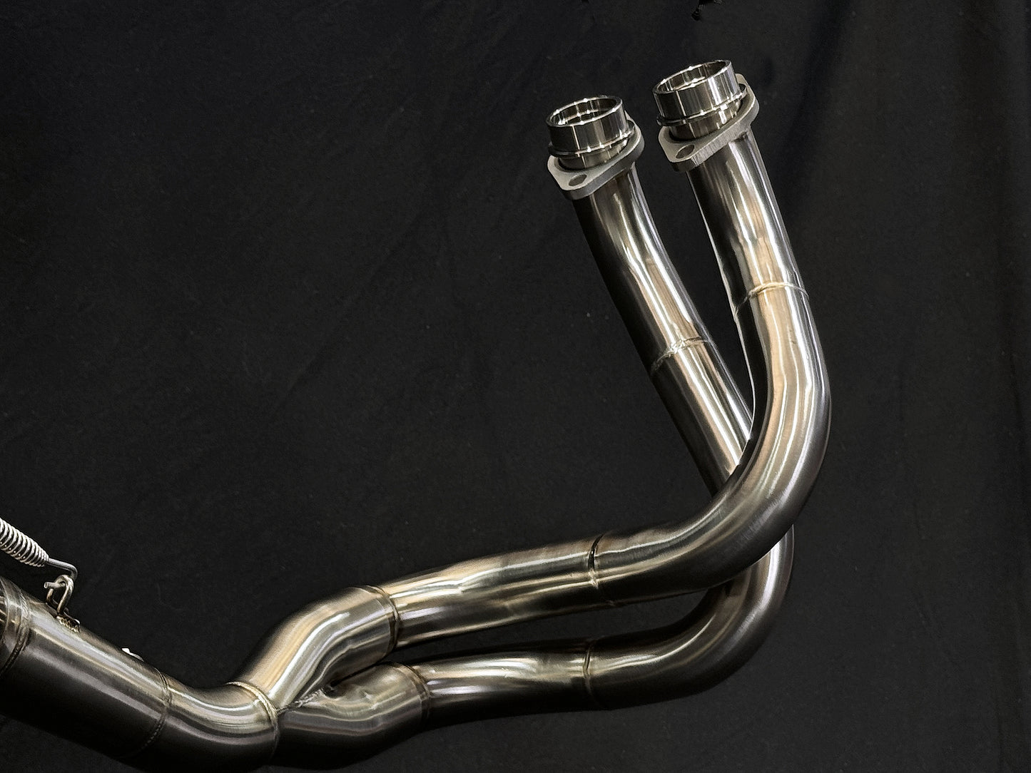 A close up view of a motorcycle's stainless steel headers.
