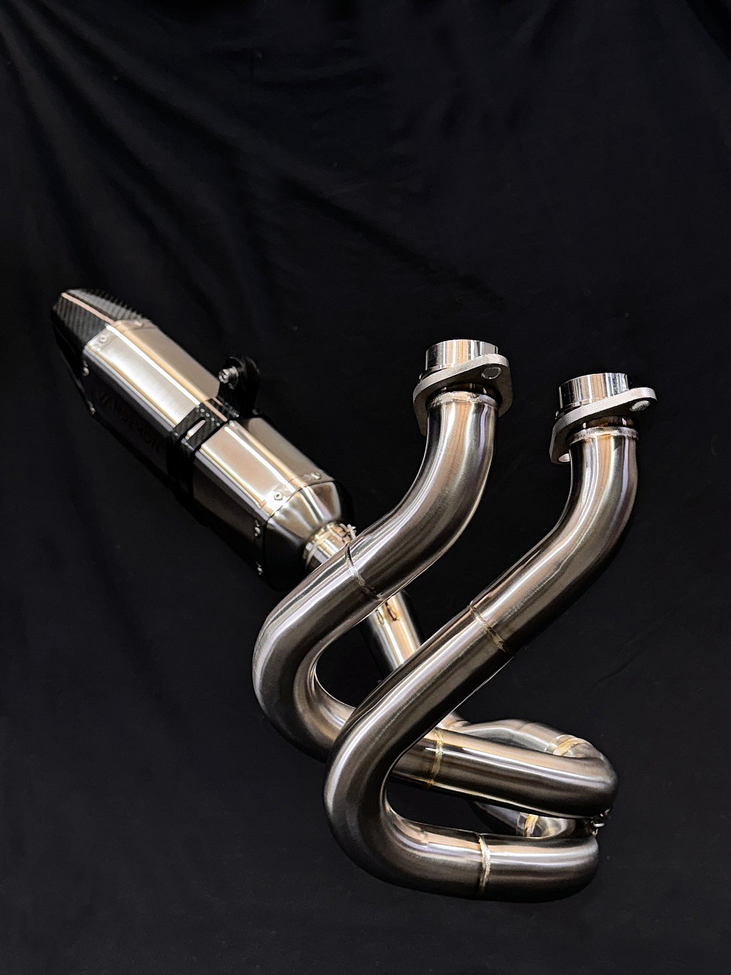 A stainless steel exhausts and elbow with a black backdrop.