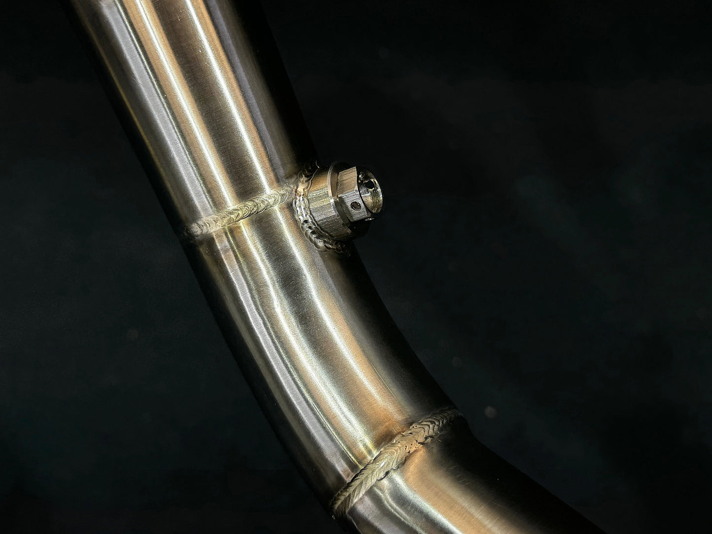 A close up view of a motorcycle's stainless steel exhausts bung.