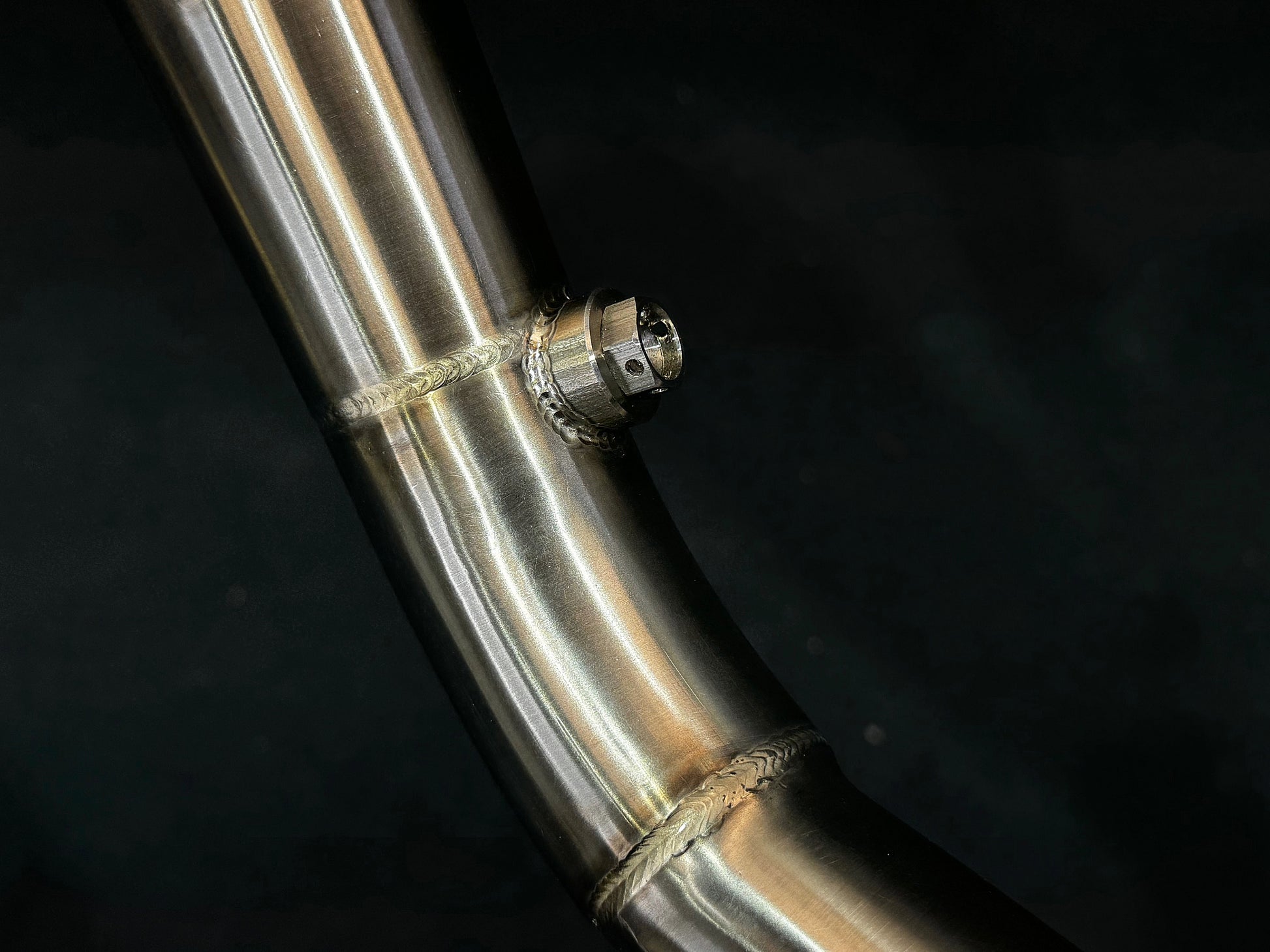 A close up view of a motorcycle's stainless steel exhausts bung.
