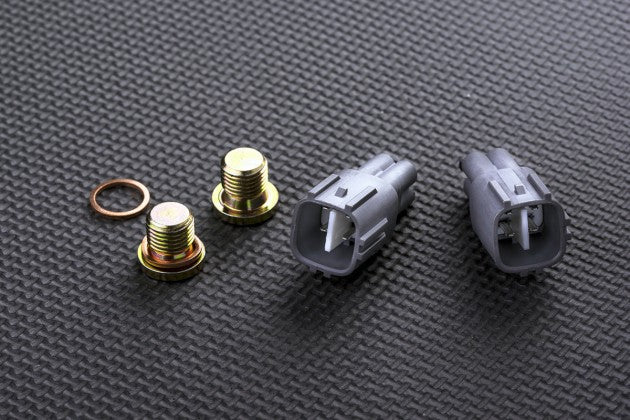 Set of automotive connectors and bolts on a textured grey surface