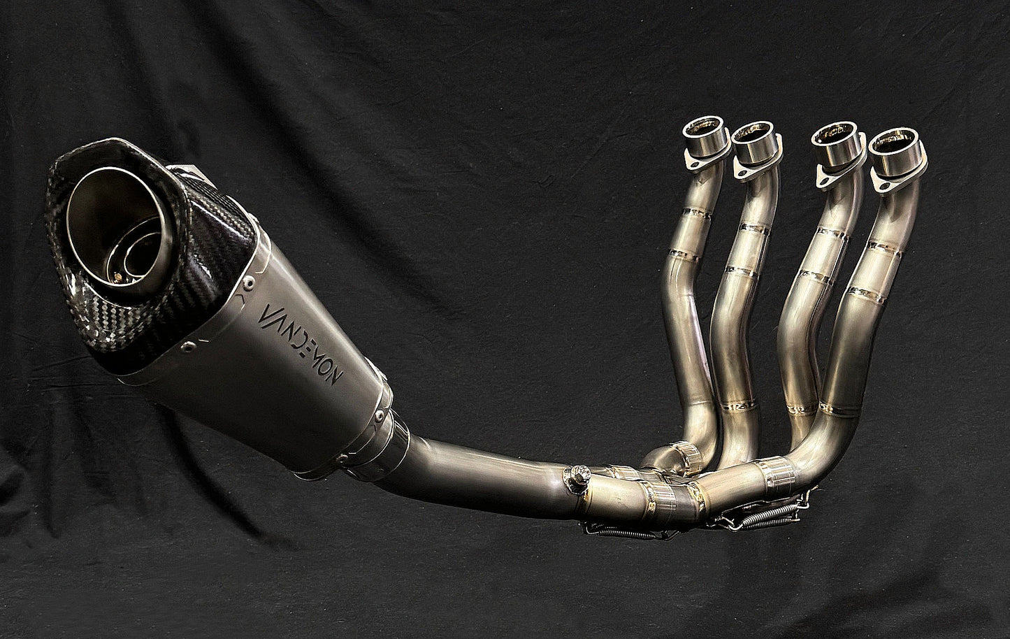 Shiny motorcycle dual-exhaust reflecting light against dark background.