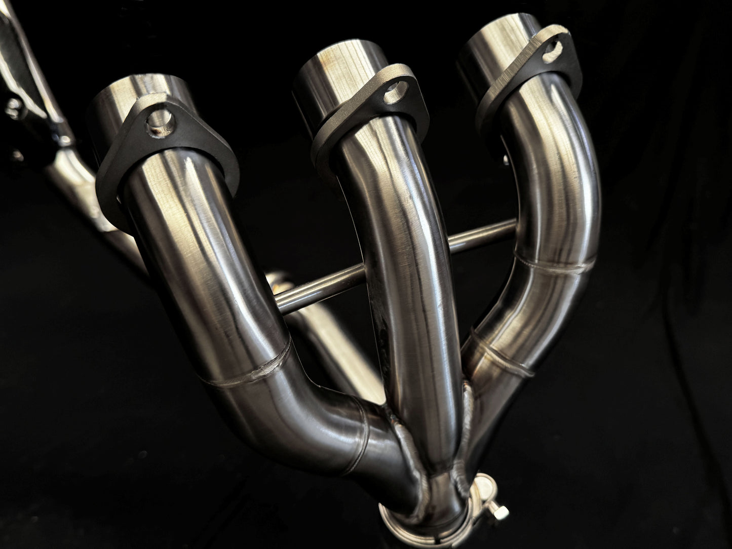 Dark background, close-up of dual-exhaust motorcycle system.