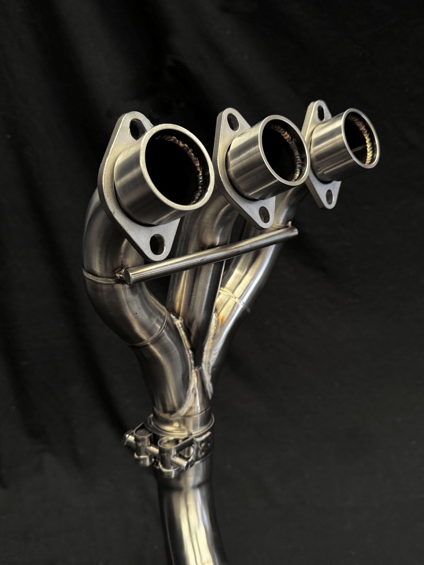 Dual-exhaust motorcycle part with detailed metallic finish.