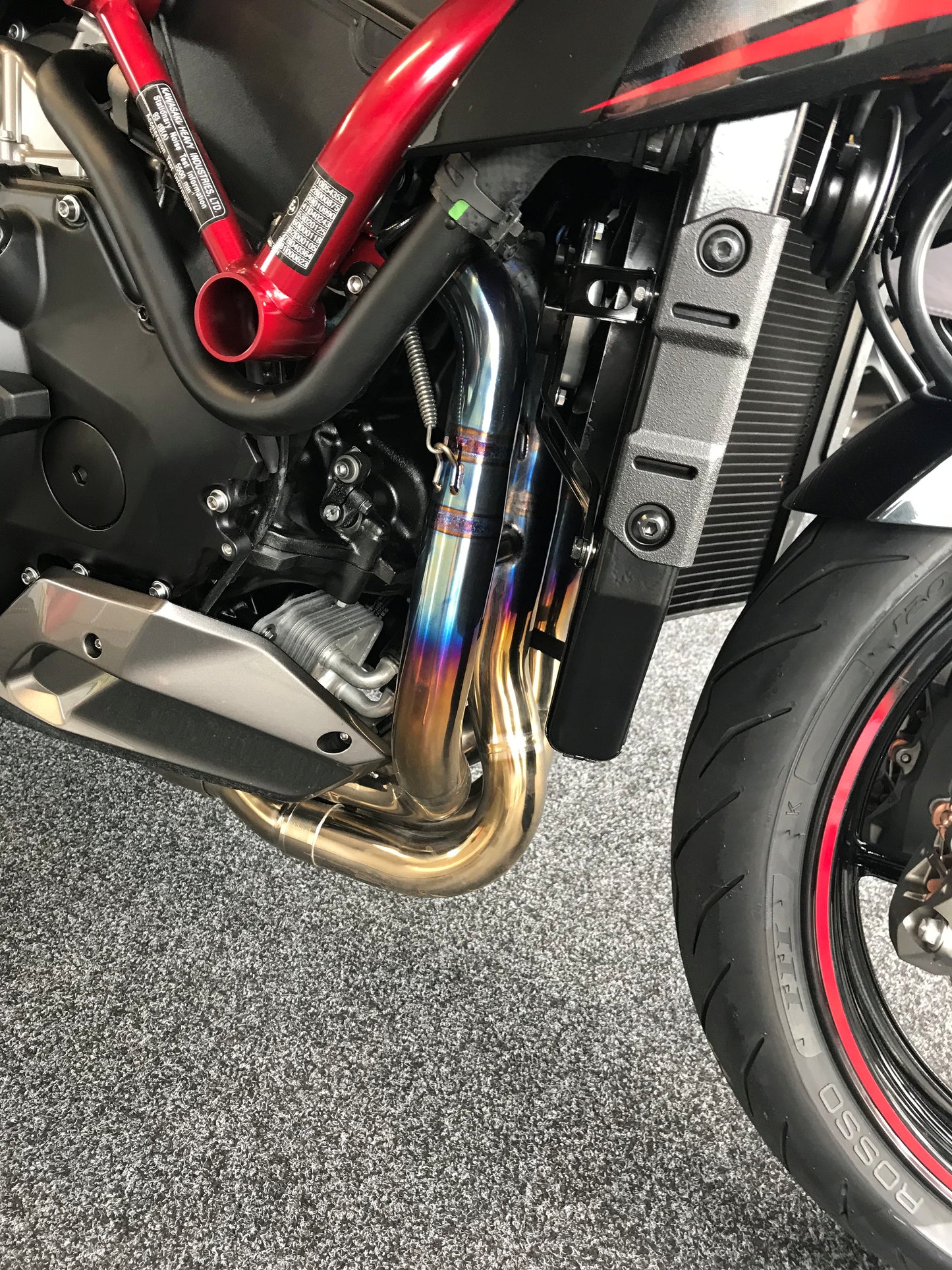 Close-up: Red motorcycle's exhaust, tire, and engine part.