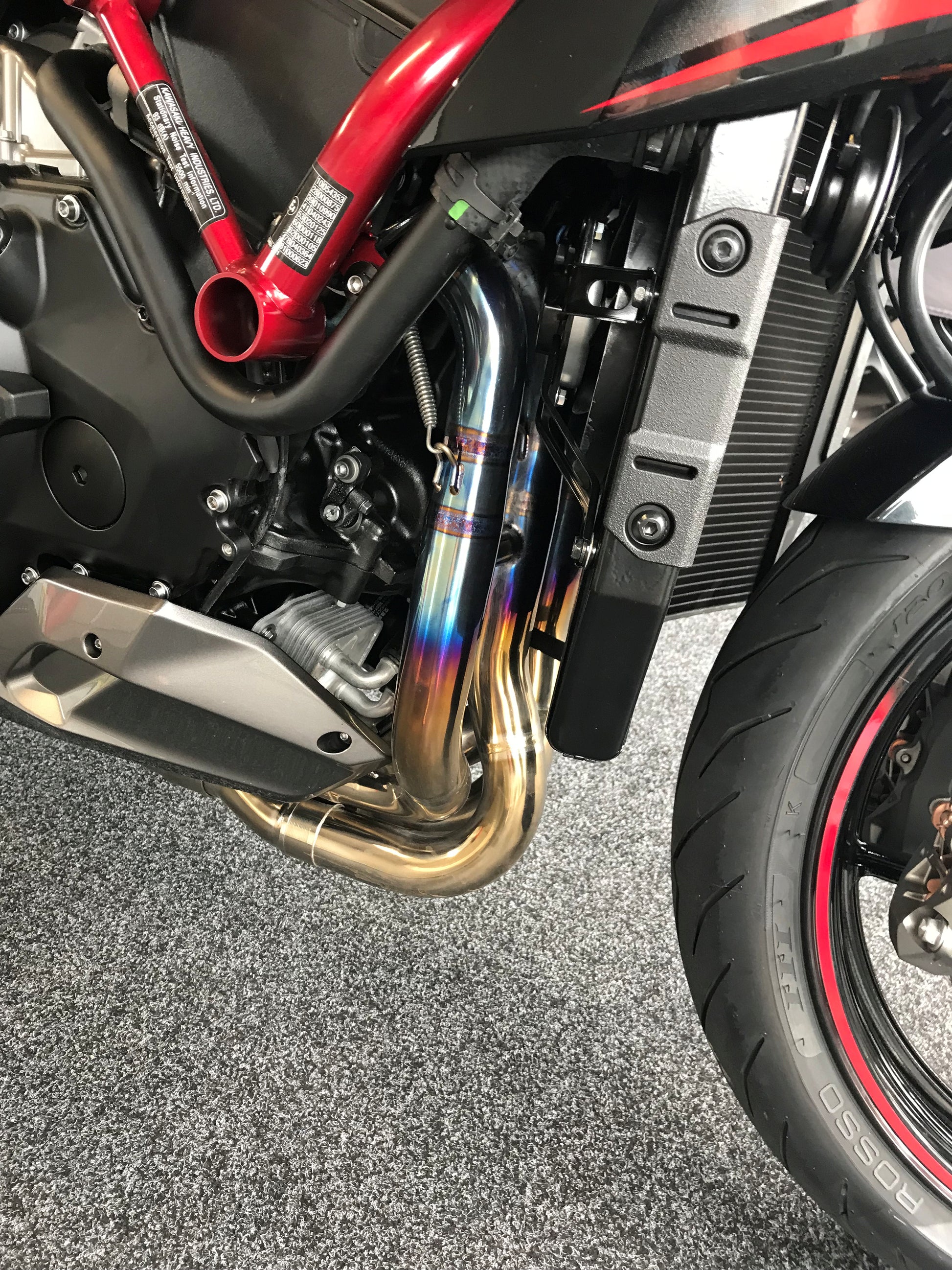 Close-up: Red motorcycle's exhaust, tire, and engine part.