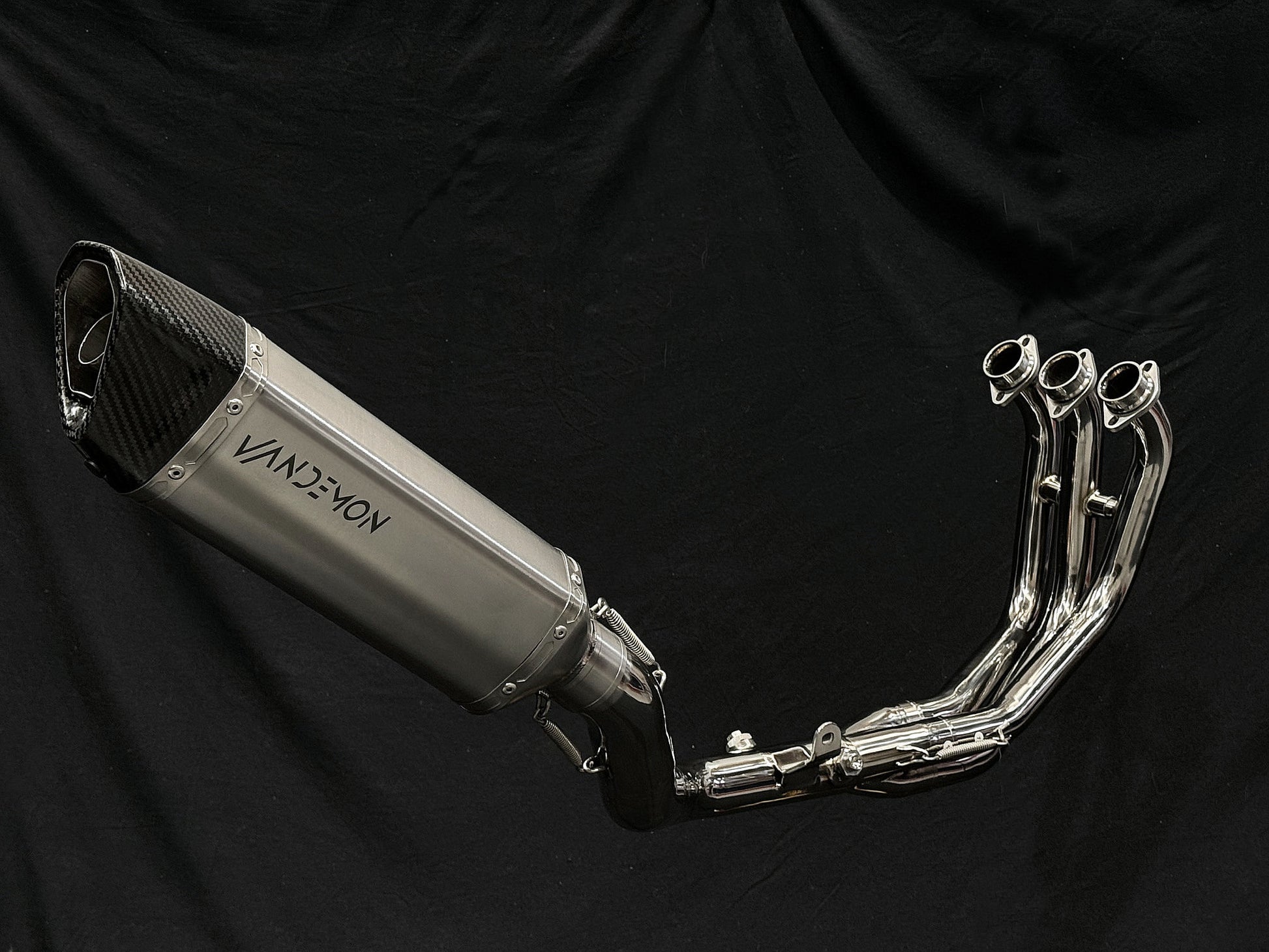 Motorcycle dual-exhaust with shiny finish against dark setting.
