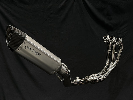 Motorcycle dual-exhaust with shiny finish against dark setting.