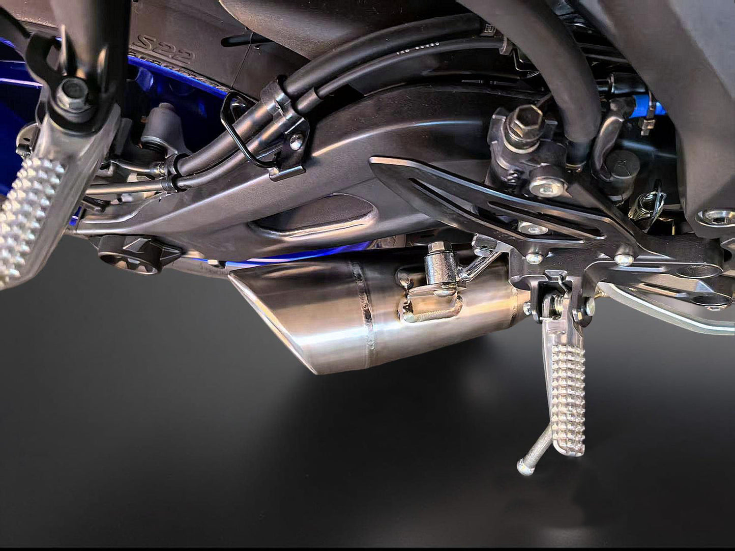 Close-up of a motorcycle's exhaust and suspension system on a dark background