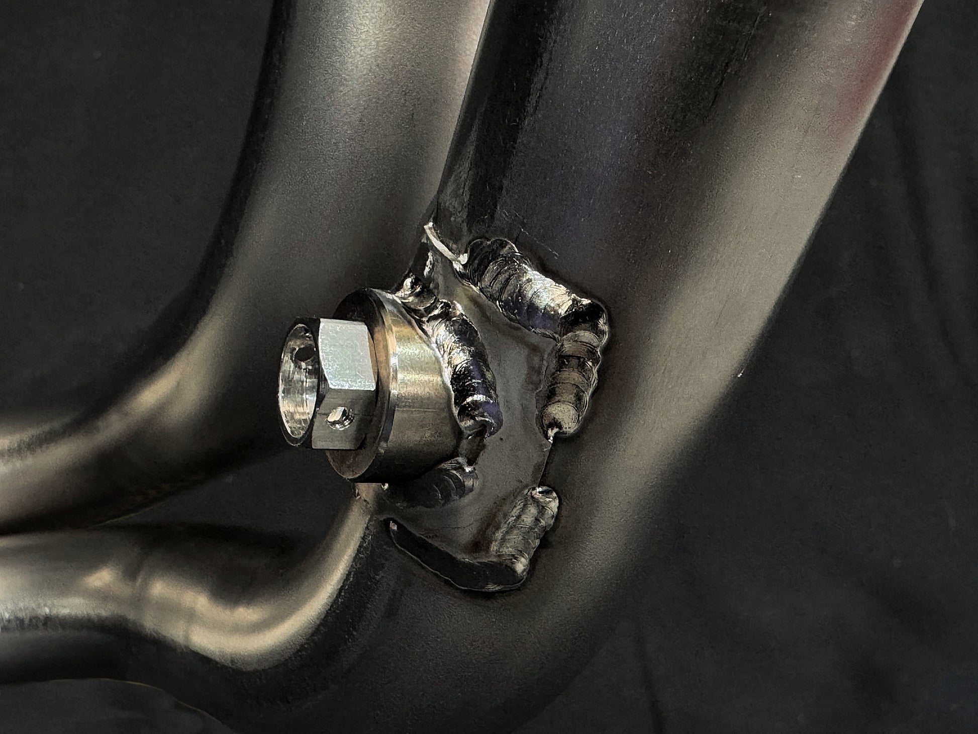 Close-up of metallic pipe assembly, precision welds, hex bolt bracket.