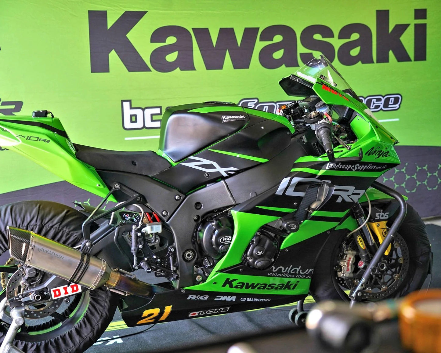 A Black and green motorcycle parked in a garage.