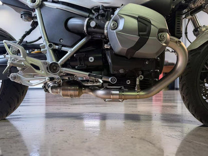 Close-up of a motorcycle's engine and exhaust system on a reflective floor.