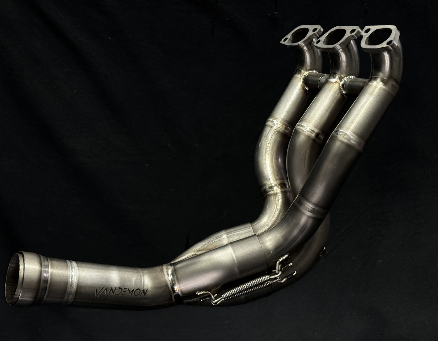 A motorcycle's titanium  exhausts headers with a black backdrop