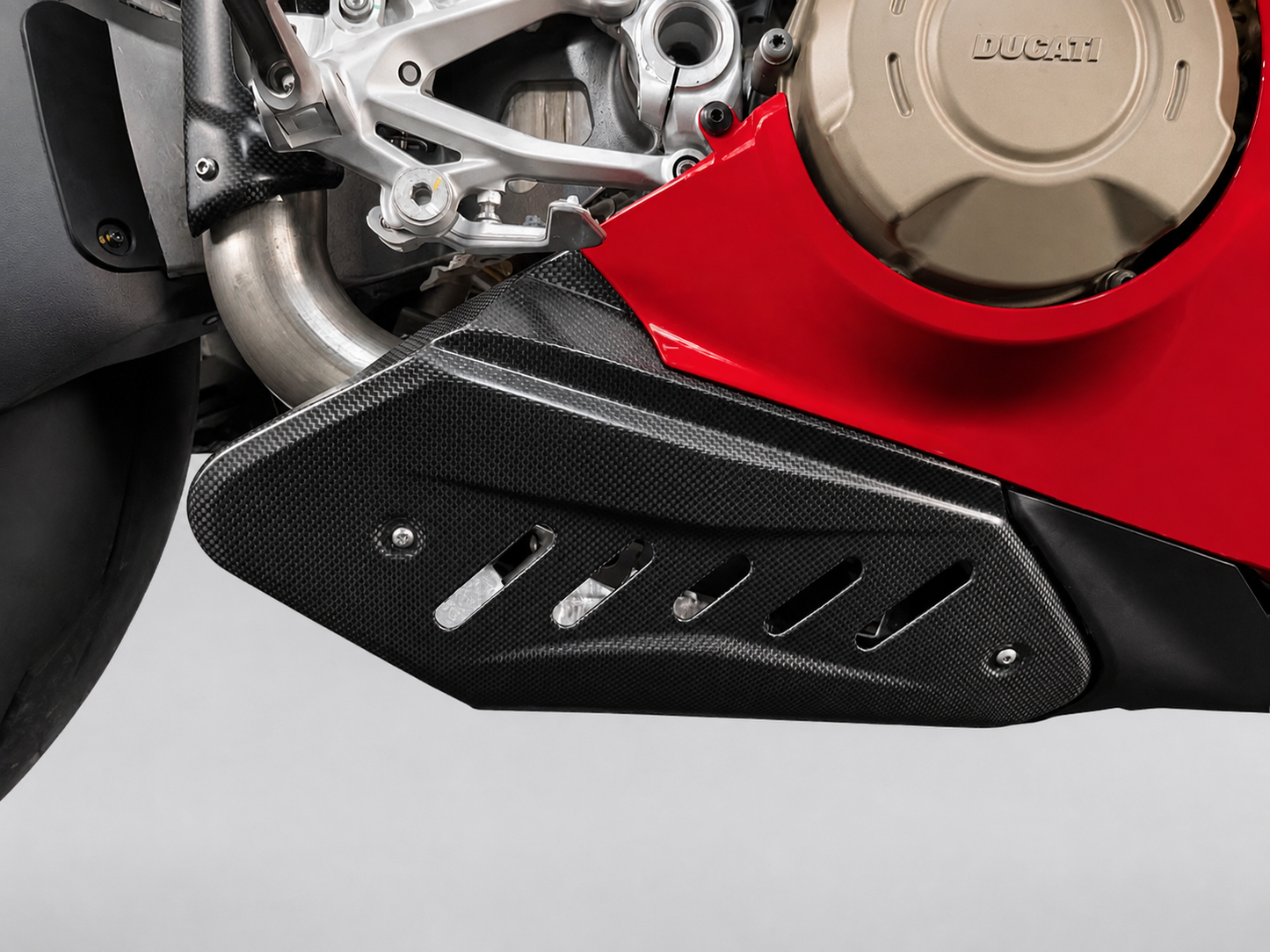 Close-up of a black carbon-fiber-textured motorcycle side cover mounted over a red Ducati engine casing.
