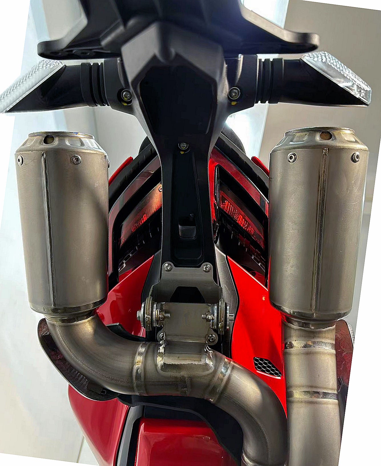 Close-up of a motorcycle exhaust system with a red engine background