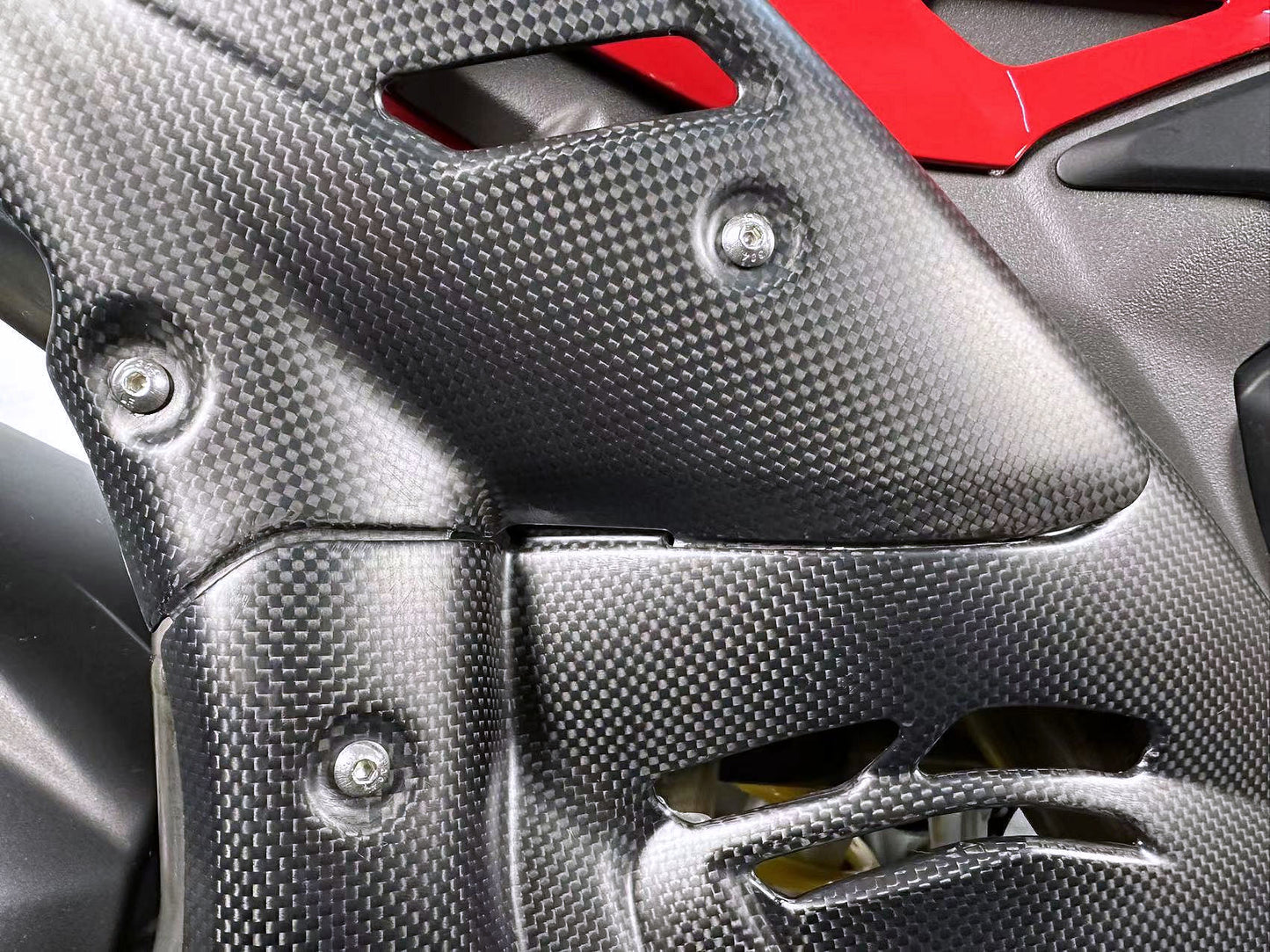 Close-up of a carbon fibre motorcycle part 2025 Panigale V4 carbon with red accents