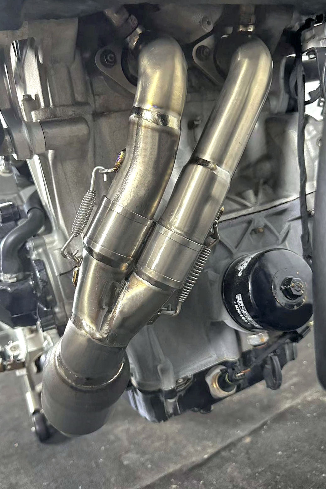 Close-up of a motorcycle engine with metallic pipes and components.